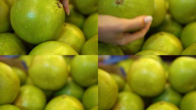 手拿绿色柚子水果。女人在超市买食物
