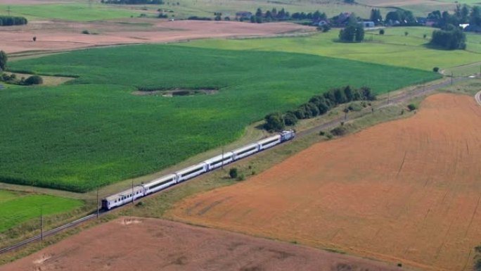 铁路上的蓝色火车。波兰公共交通基础设施的旅客列车鸟瞰图景观。客运电动火车穿过美丽的欧洲乡村的农田。
