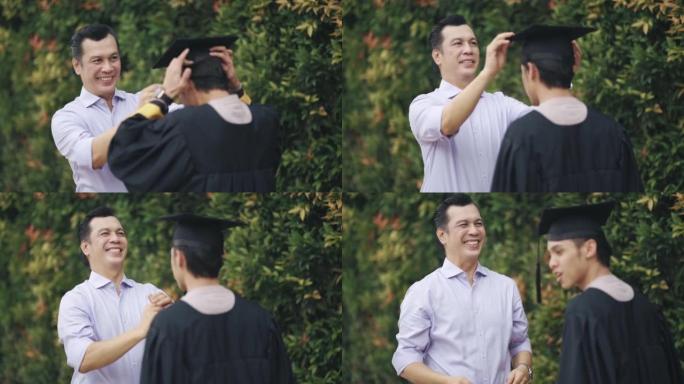 骄傲的亚洲马来父亲为他的儿子在大学大楼外的大学毕业礼服上调整了迫击炮，为毕业典礼做准备