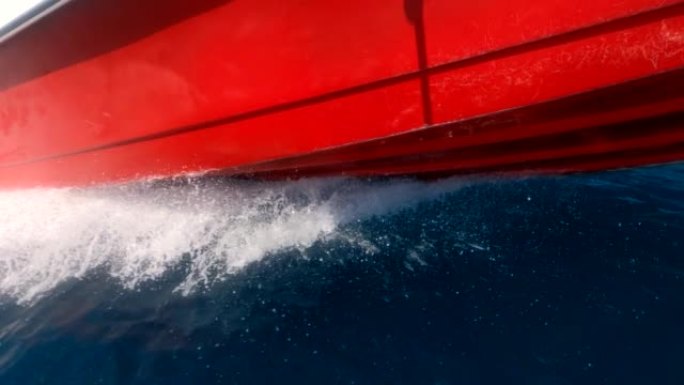 摩托艇，底角视图。海浪在快艇的侧面高速撞击。地中海绿松石水的飞溅。船的红色底部在水面上滑行。