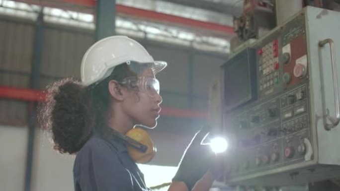 在工厂使用机械控制台面板的女工程师