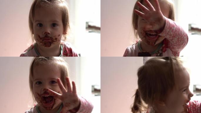 特写婴儿肮脏的脸。有趣的孩子吃巧克力。蹒跚学步的小孩早上在厨房里吃糖。幸福家庭吃糖果女孩梦想概念。生