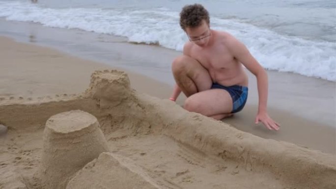 一个大男孩正在海滩上建造沙堡