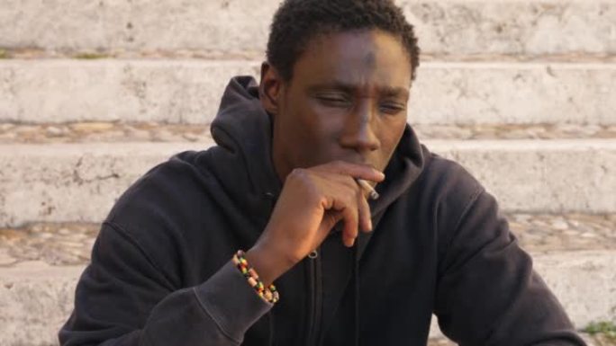 年轻的非洲男子在楼梯上抽手工香烟: 沉思的黑人吸烟