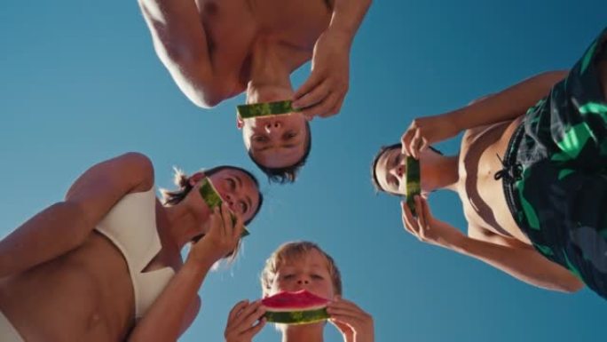 家庭吃西瓜。小男孩和他的父母在海边玩得开心。海边快乐的家庭。