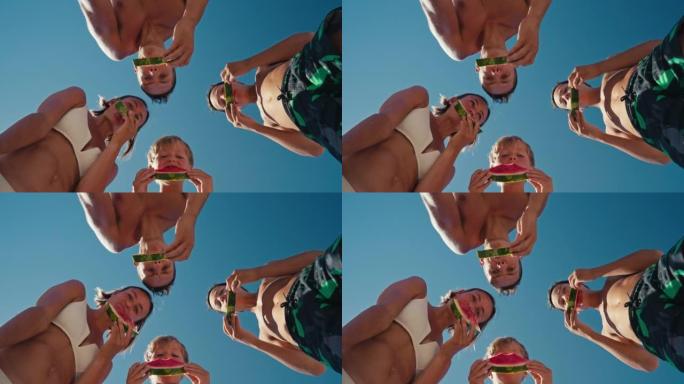家庭吃西瓜。小男孩和他的父母在海边玩得开心。海边快乐的家庭。