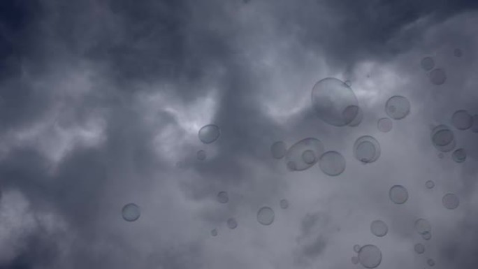 肥皂泡在灰色多云的天空背景上飞舞