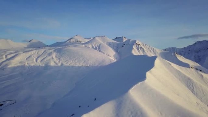 冬季日出时，雪山山坡上满是粉末的空中飞车在滑雪胜地进行自由滑行。偏远地区的山脉覆盖着初雪。高加索山峰