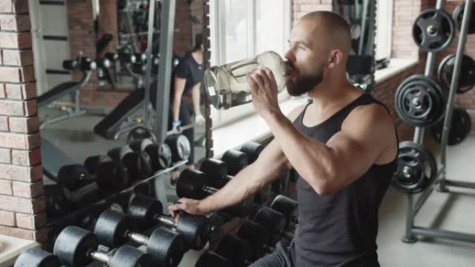 一名男子在锻炼时从健身房的瓶子里喝水