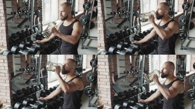一名男子在锻炼时从健身房的瓶子里喝水