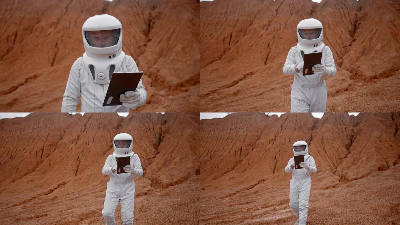 宇航员的特殊套装和头盔带着平板电脑在火星表面行走。