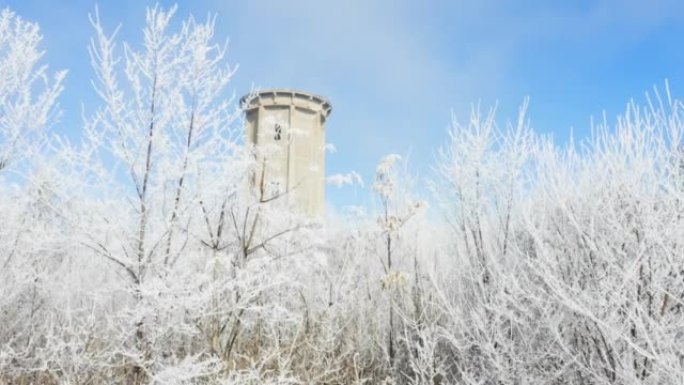 冬冬景观中冰冻森林中间的旧废弃水塔