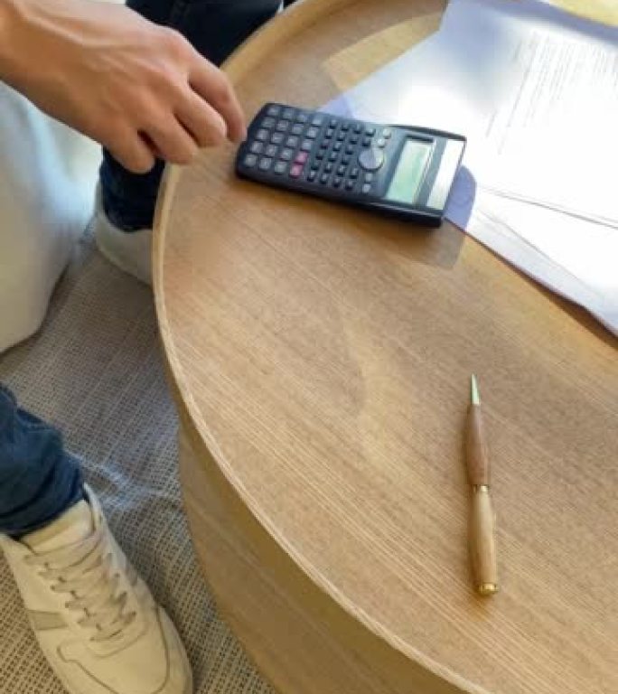 一个年轻人在家里用计算器计算着五十个欧元的账单来支付每月的房租