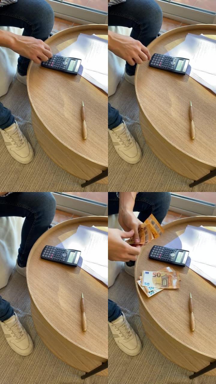 一个年轻人在家里用计算器计算着五十个欧元的账单来支付每月的房租