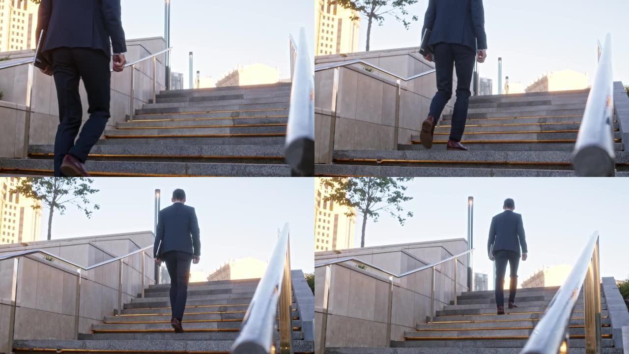面目全非的年轻商人爬上城市的背光石阶。穿着正式西装的男人，手里拿着平板电脑，穿着棕色皮靴，向前走，近