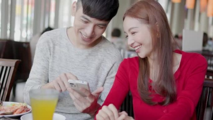 幸福的年轻夫妇在餐厅看手机