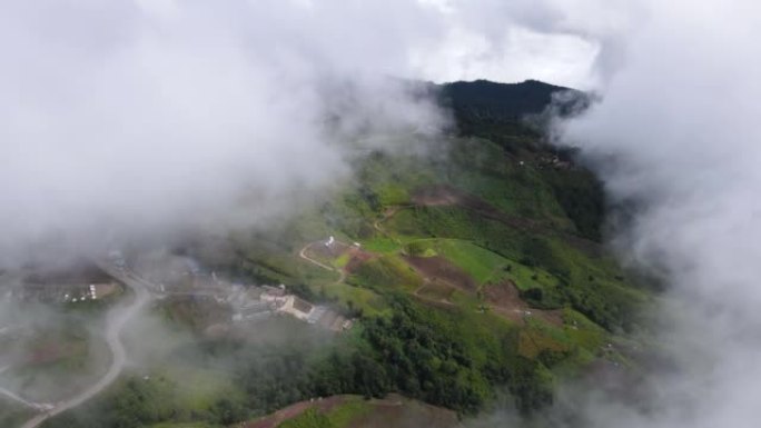 在雾气弥漫的山区上飞越村庄和农田