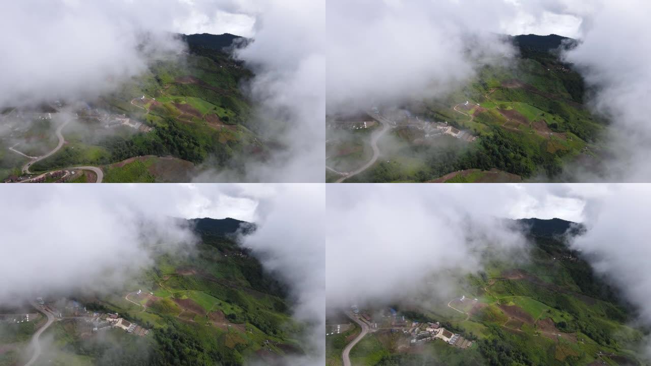 在雾气弥漫的山区上飞越村庄和农田