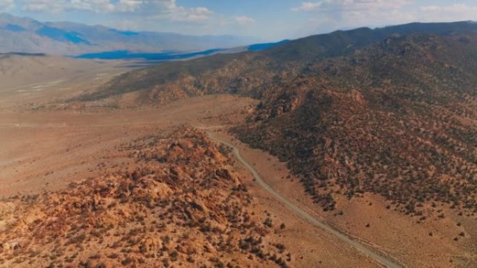 美国荒芜地区毫无生气的干燥山区景观。从空中角度看，空旷的道路沿着山脉之间的沙质领土经过。