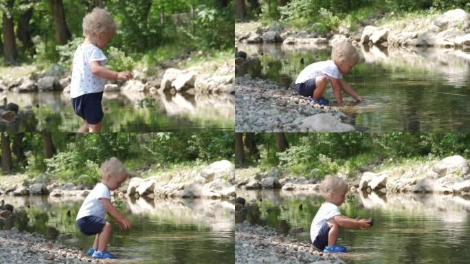 1.5岁的小孩在夏季公园的河岸上玩耍，喜欢将鹅卵石扔进水中。