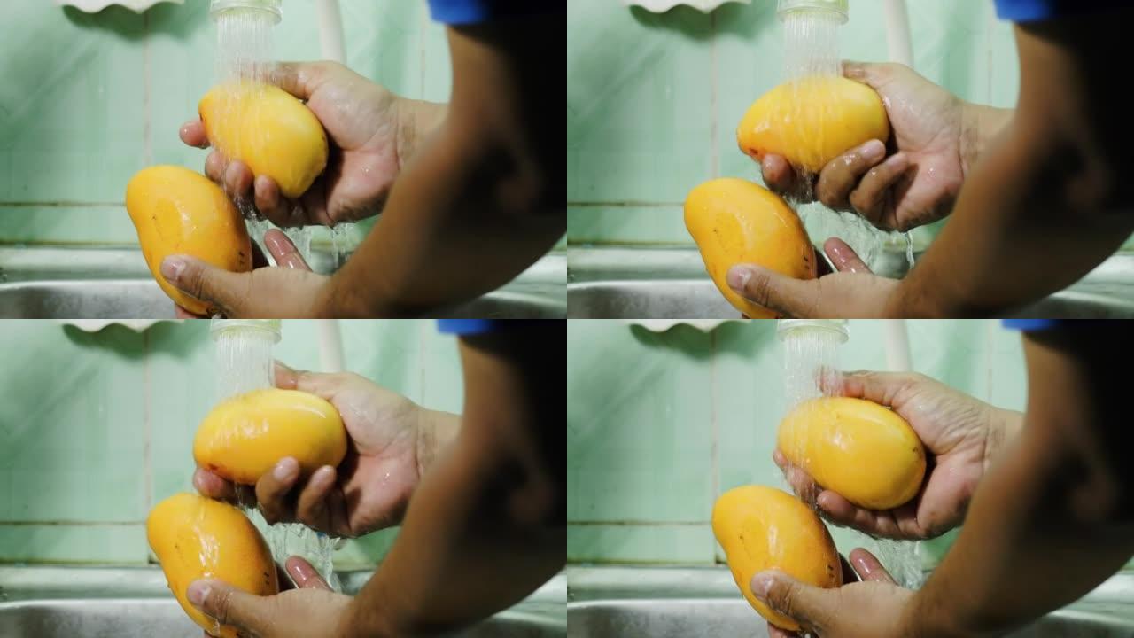 关闭男人手在家里的自来水下洗芒果型Kepodang