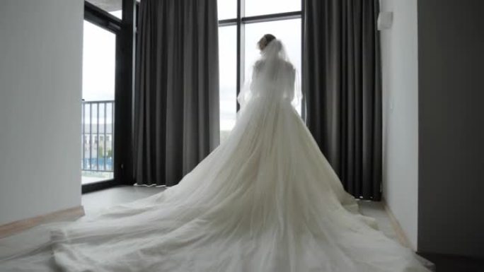 新娘穿着豪华婚纱站在窗边