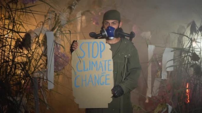 环保。一个戴着防毒面具的人拿着一张海报，上面写着 “阻止烟雾中的气候变化”。环保。空气污染。有害排放