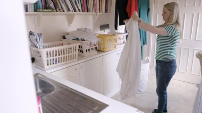 女人，在现代家庭中洗衣服和折叠衣服，用于日常家务，家务和清洁服装。新鲜亚麻布、春季清洁材料和整理床单