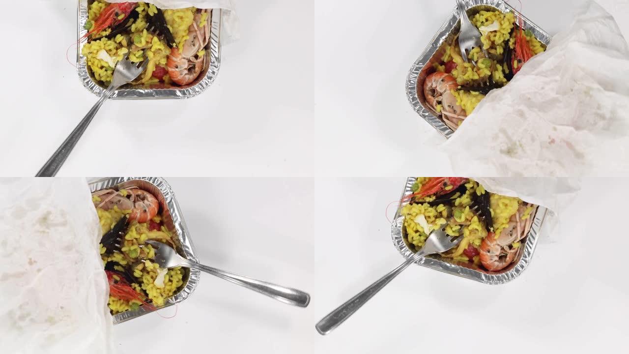 用4k拍摄的白色旋转表面的铝箔容器中的虾煮熟的米饭的俯视图