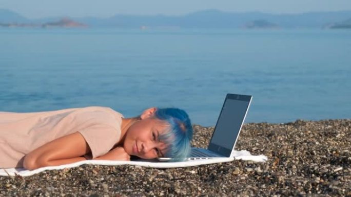 海边有笔记本电脑的懒女孩。