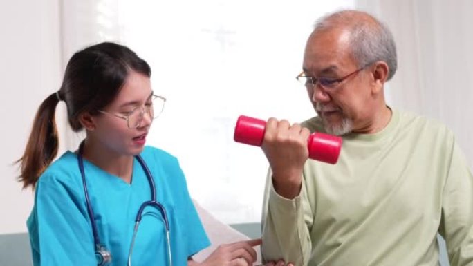 亚洲老年男性患者与护理人员一起进行物理治疗。女护士帮助从轮椅上站起来练习在家中与助行器一起散步，在疗