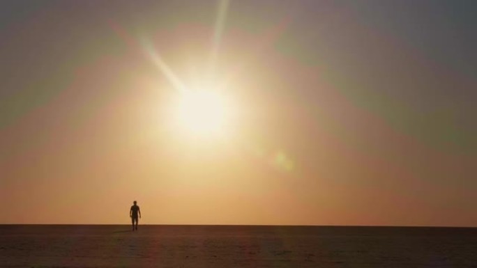 游客男性在沙漠中向后走日落的极宽镜头。