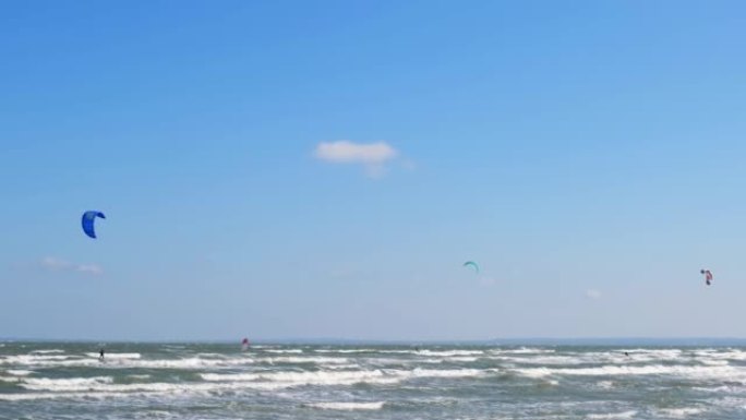 一个穿着潜水服的人穿着降落伞在海浪中滑行。一个年轻人在空中对着天空表演魔术。水上运动，风筝冲浪，滑翔