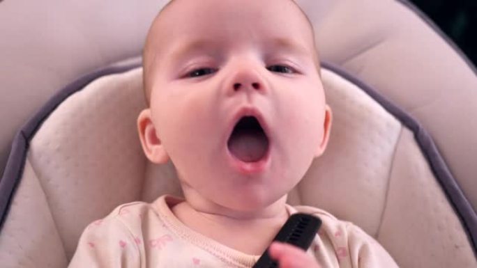 五个月的女婴躺着玩耍，试着把手表表带放进嘴里