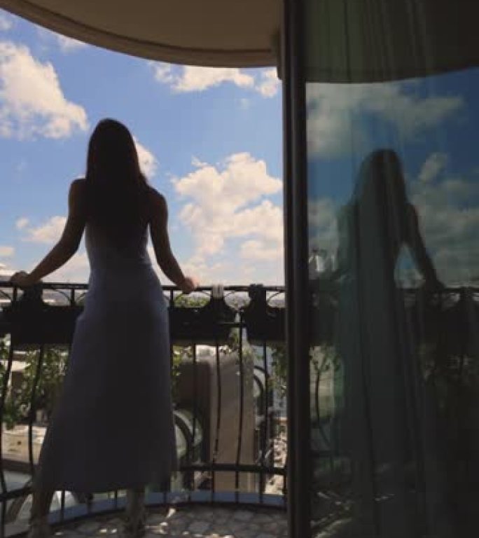 女人的剪影从酒店阳台看风景，一个穿着裙子的女人在酒店阳台上休息，看着大海和船的景色