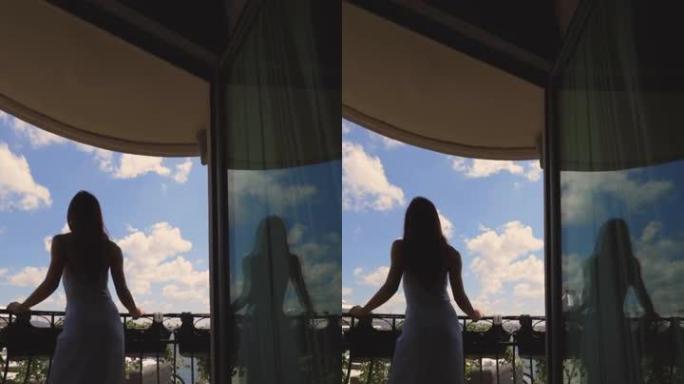 女人的剪影从酒店阳台看风景，一个穿着裙子的女人在酒店阳台上休息，看着大海和船的景色
