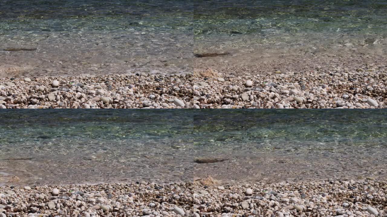 海浪特写。海浪在海滩上滚过鹅卵石。暑假概念。