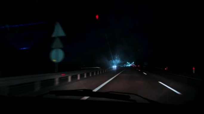 特写，夜间高速公路上行驶的汽车内部，通过挡风玻璃观看。模糊的道路，来自迎面而来的汽车前灯的bokeh