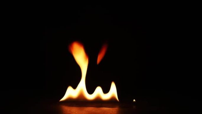 火焰点燃并燃烧。真正的火焰在黑色背景上点燃。火焰燃烧慢动作的特写镜头。