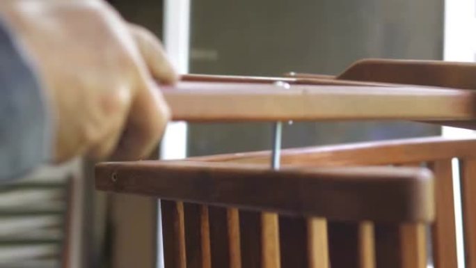 他车间里的一个木匠组装了一把手工制作的椅子，用螺丝拧紧螺栓，用六角扳手固定。检查椅子的强度。家居装饰