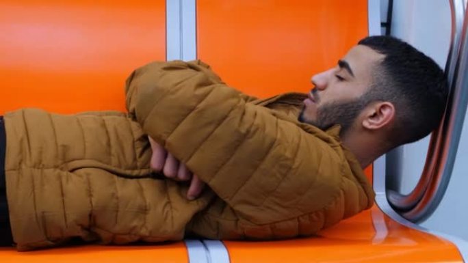 非常疲惫的北非年轻人在乘坐地铁时睡在火车上。一名突尼斯年轻人躺在地铁上睡觉