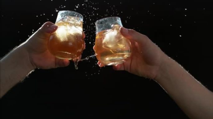 朋友叮当响威士忌酒杯的超级慢动作。庆祝生活，友谊和生日