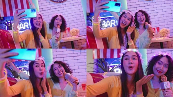 两名年轻亚洲女性的4k视频片段正在一家餐厅举行庆祝圣诞歌唱派对。开心快乐，带着微笑玩得开心。休闲活动