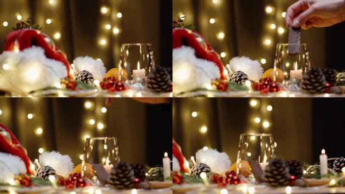 圣诞餐桌上有零散的装饰品、蜡烛和花环。我在玻璃杯里放了一块巧克力。慢动作。