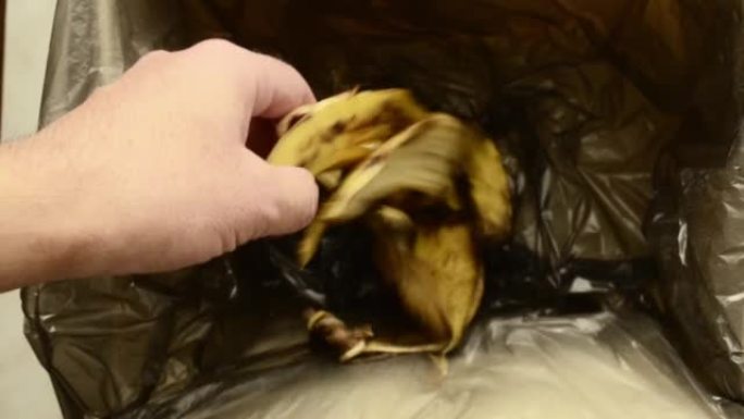 一名男子将香蕉皮扔进垃圾垃圾中。浪费食物概念