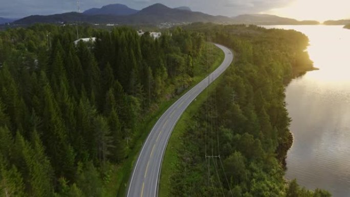 日落时挪威湖边公路上汽车的鸟瞰图