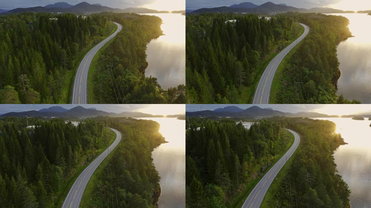 日落时挪威湖边公路上汽车的鸟瞰图