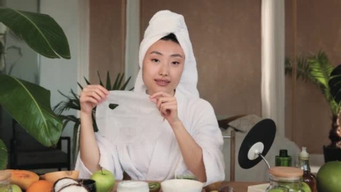 迷人的年轻亚洲女士手握棉质口罩坐在桌旁