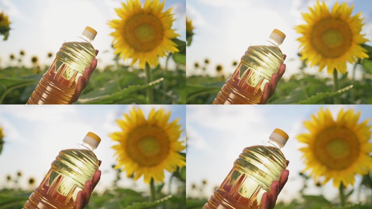 农夫的女性手拿着塑料瓶葵花籽油，背景是日落时分在田间盛开的黄色向日葵。种植向日葵作为食用油。农业企业