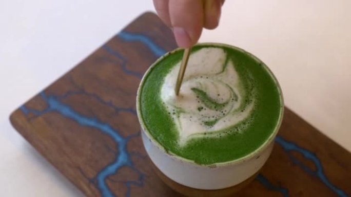 一杯热抹茶，绿色泡沫，用茶匙搅拌。咖啡的替代品，不会减少咖啡因对健康的影响。素食餐厅的时尚热生态饮料